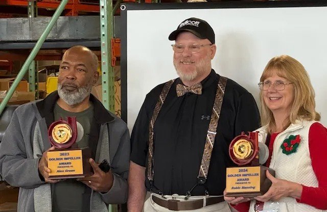two award winners hold their plaques while posing for a photo with the CEO of Ellicott Dredges