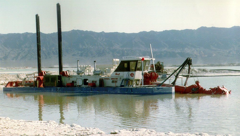 dredge on the water with mountains in the background
